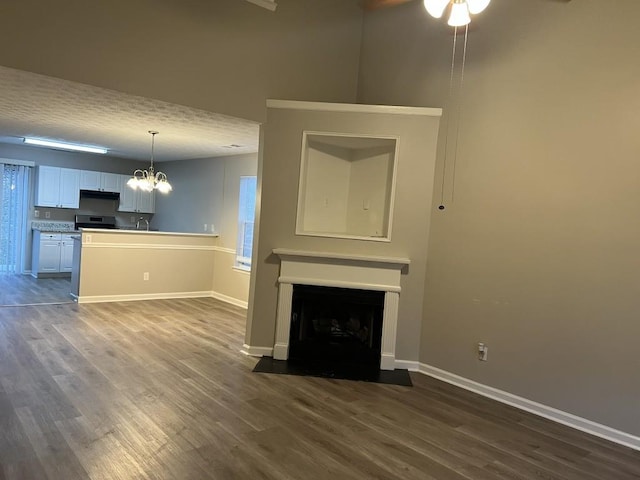 unfurnished living room with ceiling fan with notable chandelier, dark hardwood / wood-style flooring, and sink