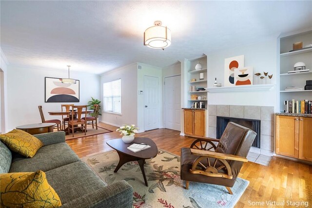 1150 Collier Rd NW Unit G8, Atlanta, GA 30318 - living room featuring light wood-style floors, built in shelves, a tiled fireplace, and ornamental molding