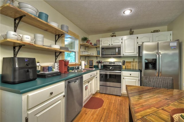 276 Pine Ridge Rd, Ellijay, GA 30536 - kitchen with appliances with stainless steel finishes, open shelves, dark countertops, a textured ceiling, and light wood-style flooring