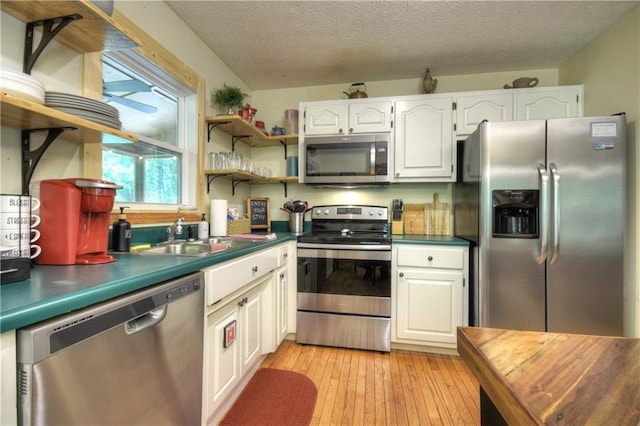276 Pine Ridge Rd, Ellijay, GA 30536 - kitchen featuring stainless steel appliances, dark countertops, white cabinets, light wood-type flooring, and a textured ceiling