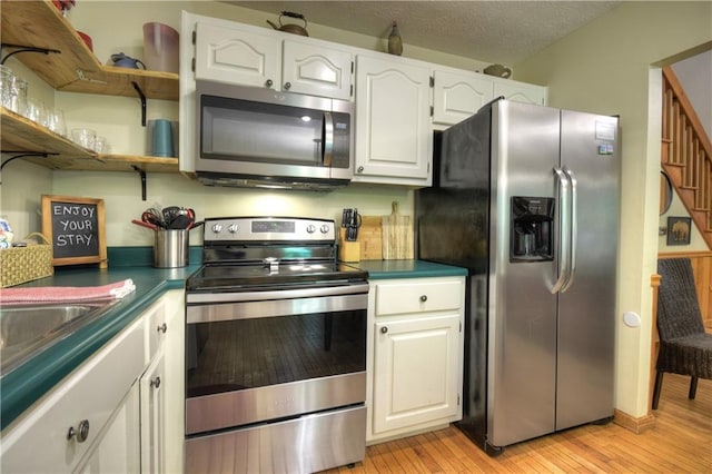 276 Pine Ridge Rd, Ellijay, GA 30536 - kitchen with stainless steel appliances, light wood finished floors, dark countertops, and white cabinets