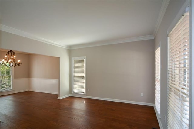 unfurnished room with an inviting chandelier, crown molding, a wainscoted wall, and dark wood finished floors