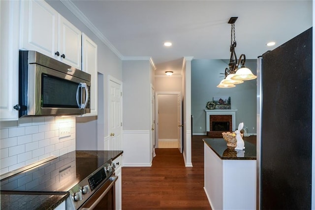 kitchen featuring dark wood-style flooring, white cabinets, decorative light fixtures, decorative backsplash, and appliances with stainless steel finishes
