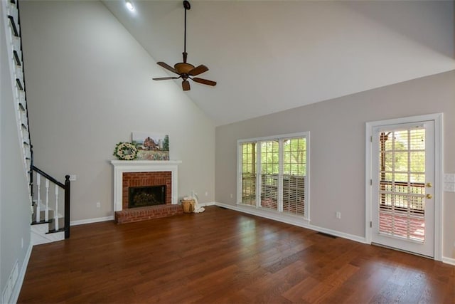unfurnished living room featuring high vaulted ceiling, a ceiling fan, wood finished floors, a brick fireplace, and baseboards
