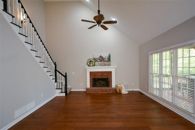 unfurnished living room featuring stairs, a brick fireplace, ceiling fan, high vaulted ceiling, and wood finished floors