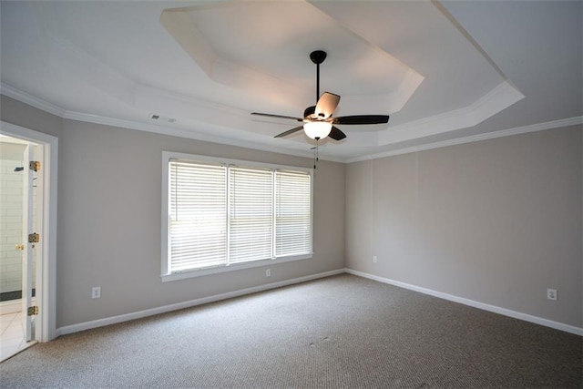 carpeted empty room featuring a raised ceiling, ceiling fan, ornamental molding, and visible vents
