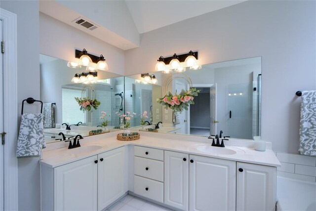 bathroom with tiled shower, double vanity, visible vents, and vaulted ceiling