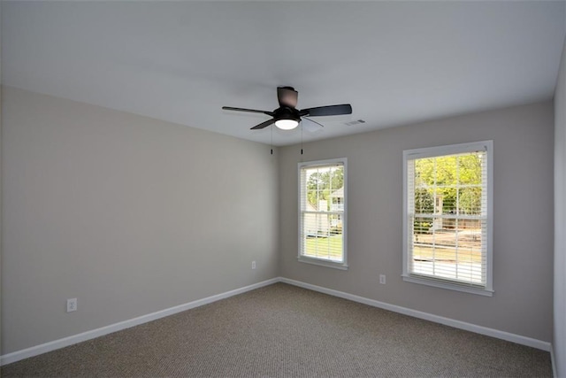 carpeted spare room featuring visible vents, baseboards, and a ceiling fan