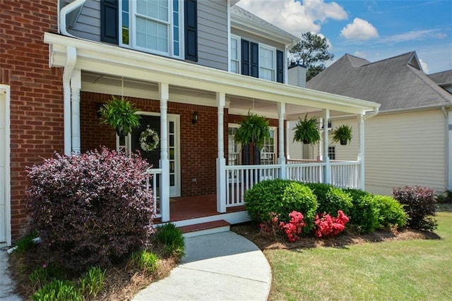 property entrance featuring a porch and brick siding