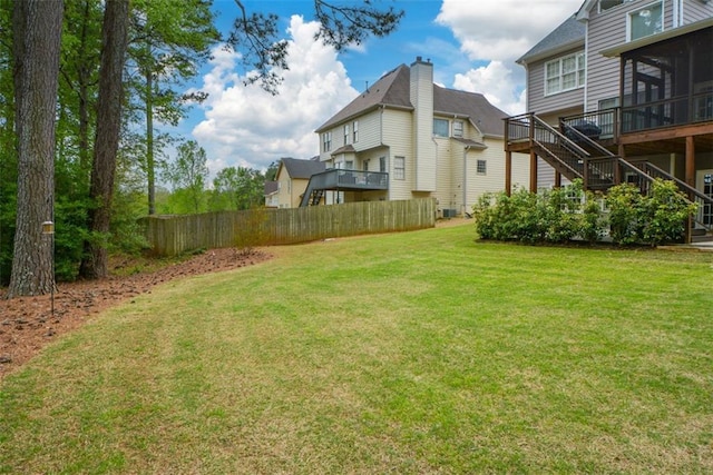 view of yard featuring a sunroom, fence, and stairway