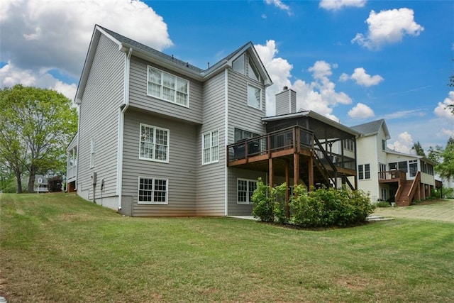 back of house featuring a chimney, a deck, and a lawn