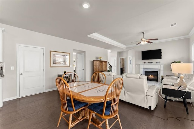 dining room with ceiling fan, ornamental molding, dark hardwood / wood-style flooring, and a tray ceiling