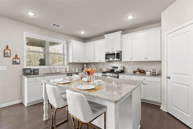 kitchen with a kitchen island, appliances with stainless steel finishes, sink, and white cabinets