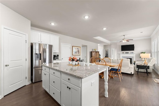 kitchen with white cabinetry, light stone counters, stainless steel fridge, and a center island