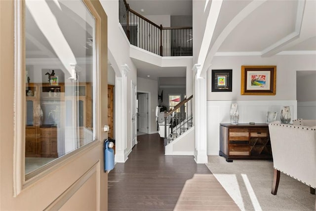 foyer entrance featuring hardwood / wood-style flooring, ornamental molding, and ornate columns