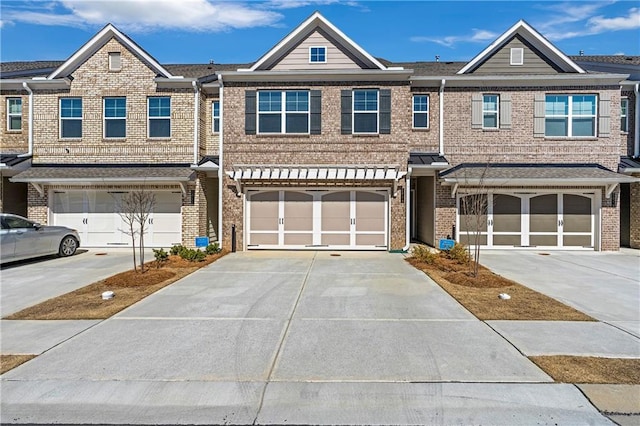 multi unit property featuring a garage, driveway, and brick siding