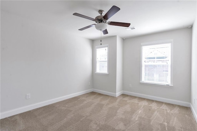 spare room with light carpet, baseboards, visible vents, and ceiling fan