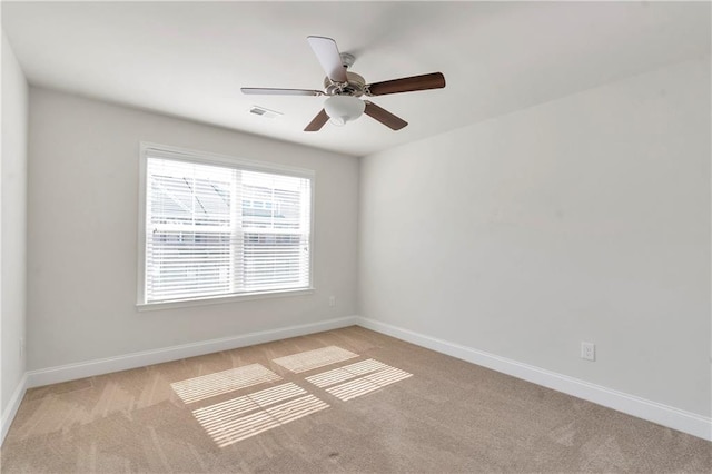 unfurnished room with visible vents, a ceiling fan, light colored carpet, and baseboards