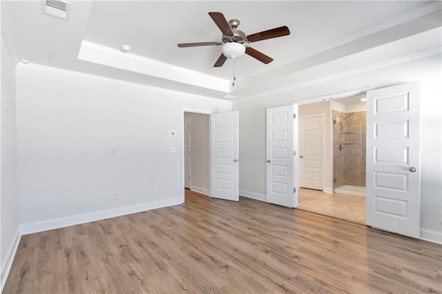 unfurnished bedroom featuring light wood-type flooring, a tray ceiling, and ornamental molding