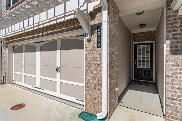 view of exterior entry with a garage and brick siding