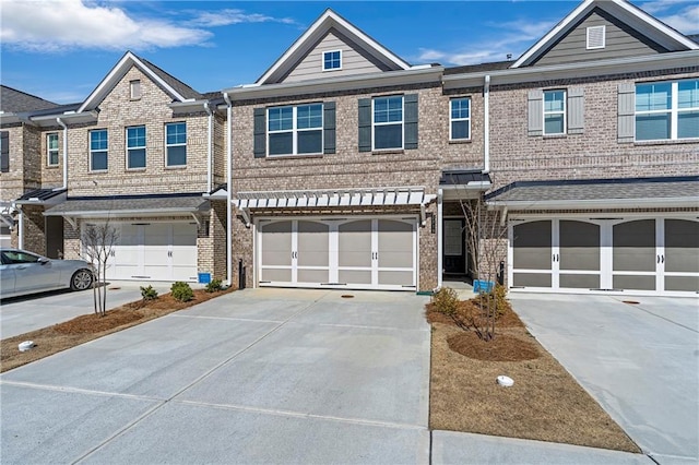 view of property featuring an attached garage, concrete driveway, and brick siding