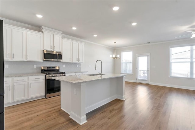 kitchen featuring appliances with stainless steel finishes, crown molding, a sink, and tasteful backsplash