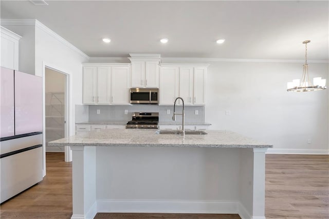 kitchen with light wood finished floors, appliances with stainless steel finishes, a sink, and tasteful backsplash