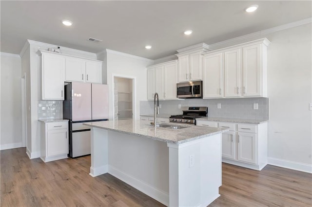 kitchen with stainless steel appliances, visible vents, a sink, and white cabinetry