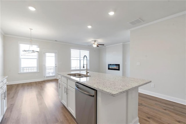 kitchen with crown molding, visible vents, a glass covered fireplace, a sink, and dishwasher