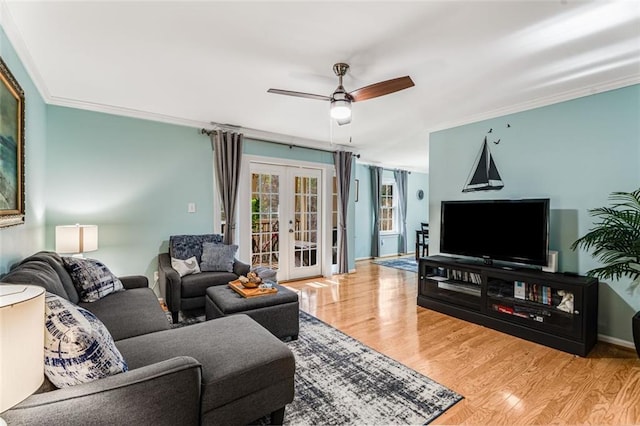 living area featuring ceiling fan, wood finished floors, baseboards, french doors, and crown molding