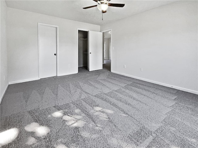 unfurnished bedroom with ceiling fan, multiple closets, and dark colored carpet