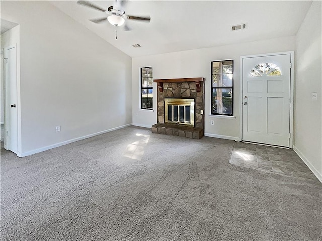 unfurnished living room with ceiling fan, a stone fireplace, vaulted ceiling, and carpet flooring