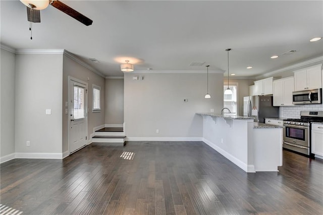 kitchen featuring a kitchen breakfast bar, decorative backsplash, light stone countertops, appliances with stainless steel finishes, and white cabinetry