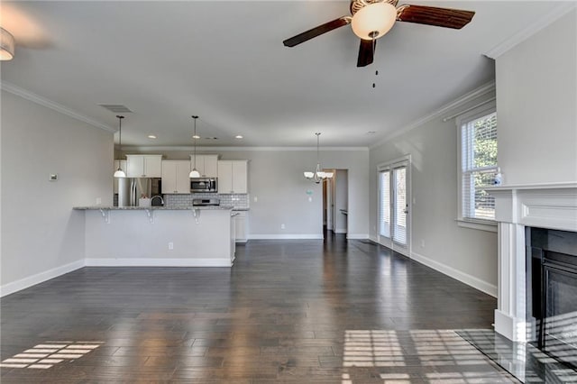 unfurnished living room featuring ceiling fan with notable chandelier, dark hardwood / wood-style floors, and ornamental molding