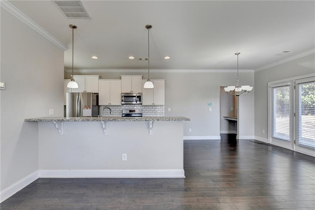 kitchen with a kitchen breakfast bar, white cabinetry, stainless steel appliances, and hanging light fixtures