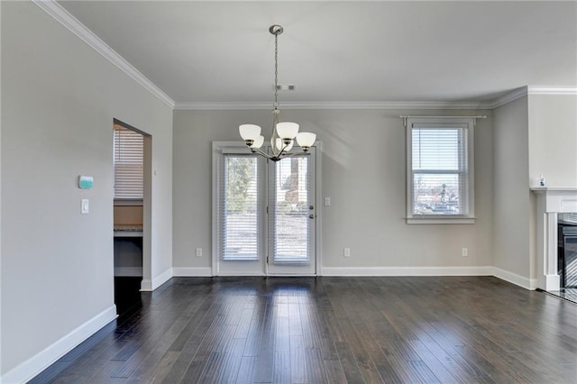 unfurnished dining area featuring plenty of natural light, dark hardwood / wood-style flooring, crown molding, and an inviting chandelier