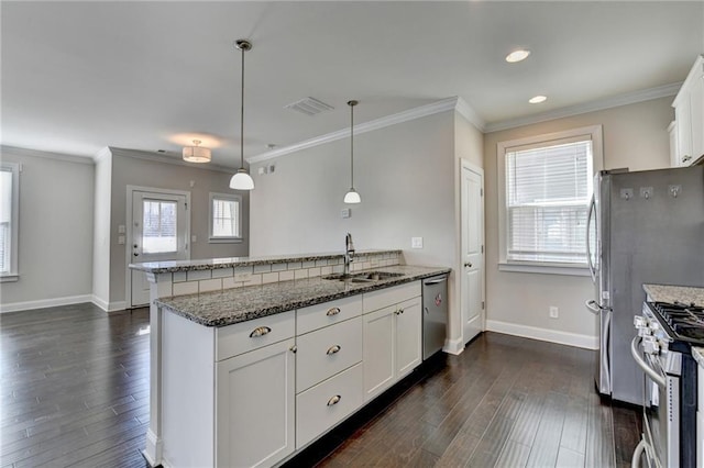 kitchen featuring stainless steel appliances, sink, pendant lighting, dark stone countertops, and white cabinetry