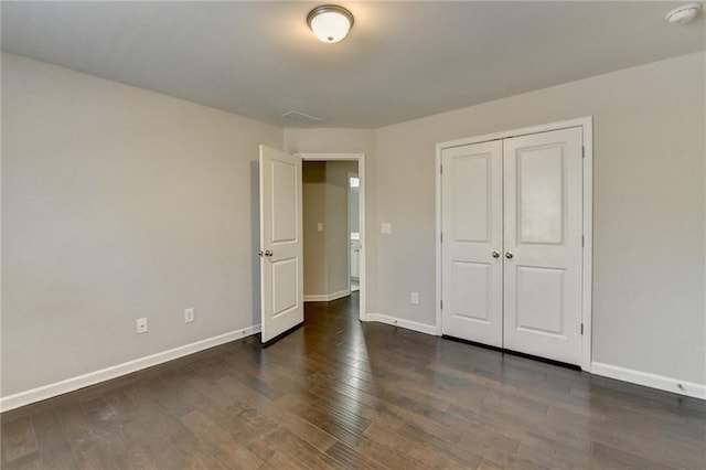 unfurnished bedroom with a closet and dark wood-type flooring