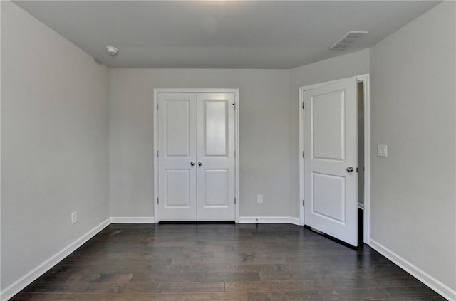 unfurnished bedroom featuring dark hardwood / wood-style floors and a closet