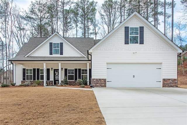 view of front of home featuring a shingled roof, a front yard, covered porch, stone siding, and driveway