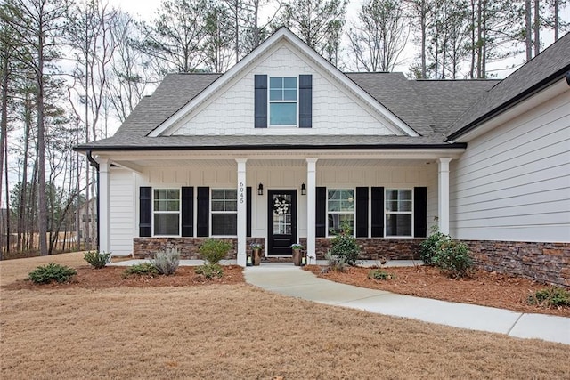 view of front of house with a porch, board and batten siding, a front yard, and a shingled roof