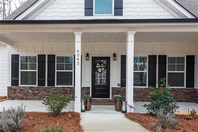 property entrance featuring stone siding and covered porch