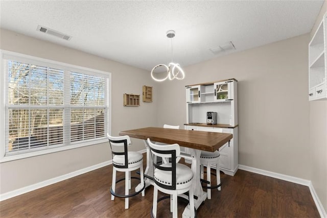 dining room featuring dark wood-type flooring, a textured ceiling, and a notable chandelier