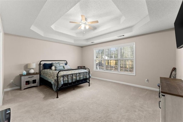 bedroom with light carpet, ceiling fan, a raised ceiling, and a textured ceiling