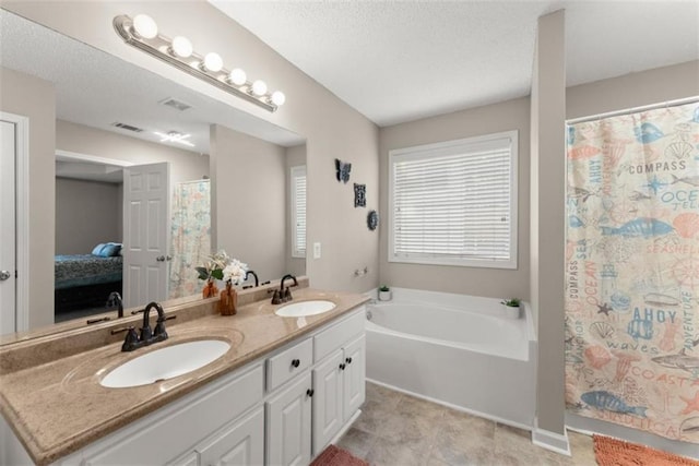 bathroom featuring vanity, a bath, tile patterned floors, and a textured ceiling