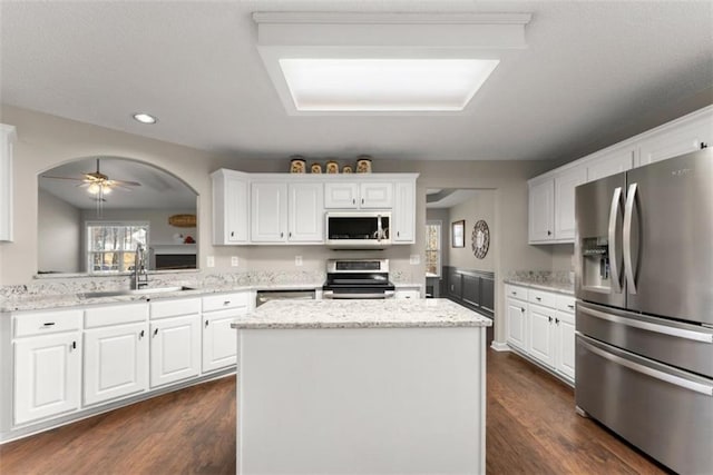 kitchen with white cabinetry, sink, stainless steel appliances, and a center island