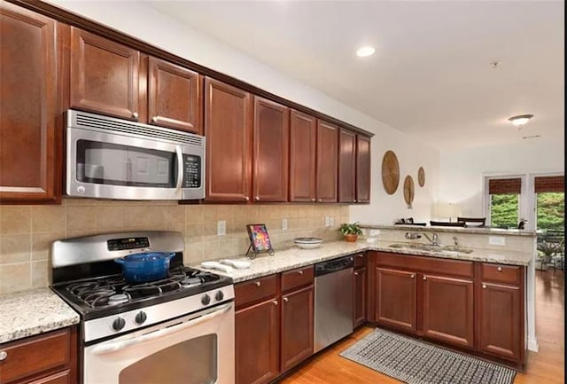 6038 Mayfield Way SE, Mableton, GA 30126 - kitchen featuring appliances with stainless steel finishes, a peninsula, backsplash, light wood-type flooring, and light stone countertops