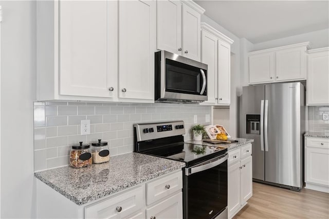 kitchen featuring light stone countertops, light hardwood / wood-style flooring, stainless steel appliances, backsplash, and white cabinets