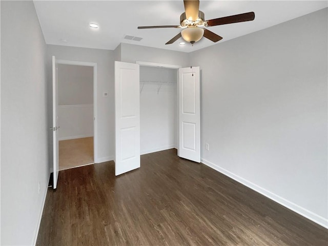 unfurnished bedroom featuring ceiling fan, a closet, and dark wood-type flooring