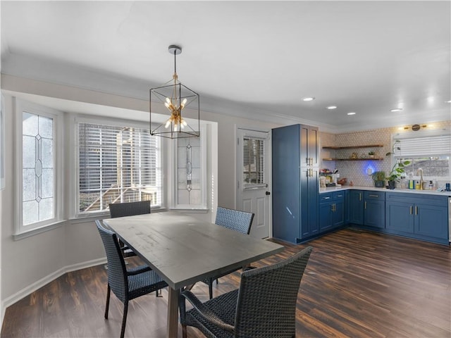 dining space with dark wood-style flooring, crown molding, baseboards, and an inviting chandelier